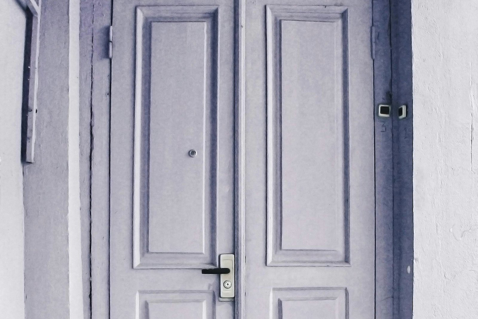 Hand mit Werkzeug an einem Türscharnier während der Einstellung